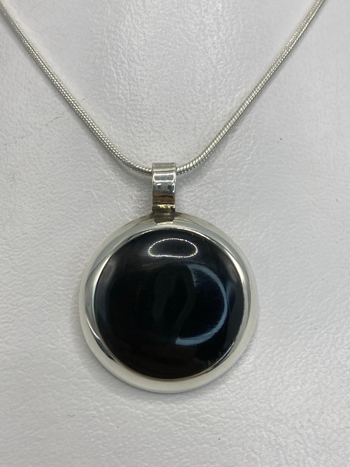 Dije de plata 925 con ónix negro engastado, colgando de una cadena de plata en forma de serpentina