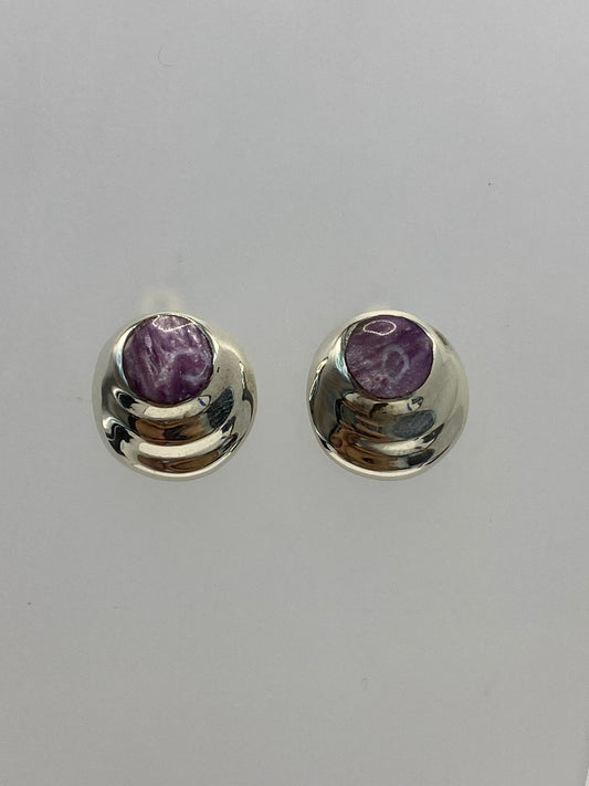 Detalle frontal de los aretes mostrando la incrustación de la piedra morada en la plata