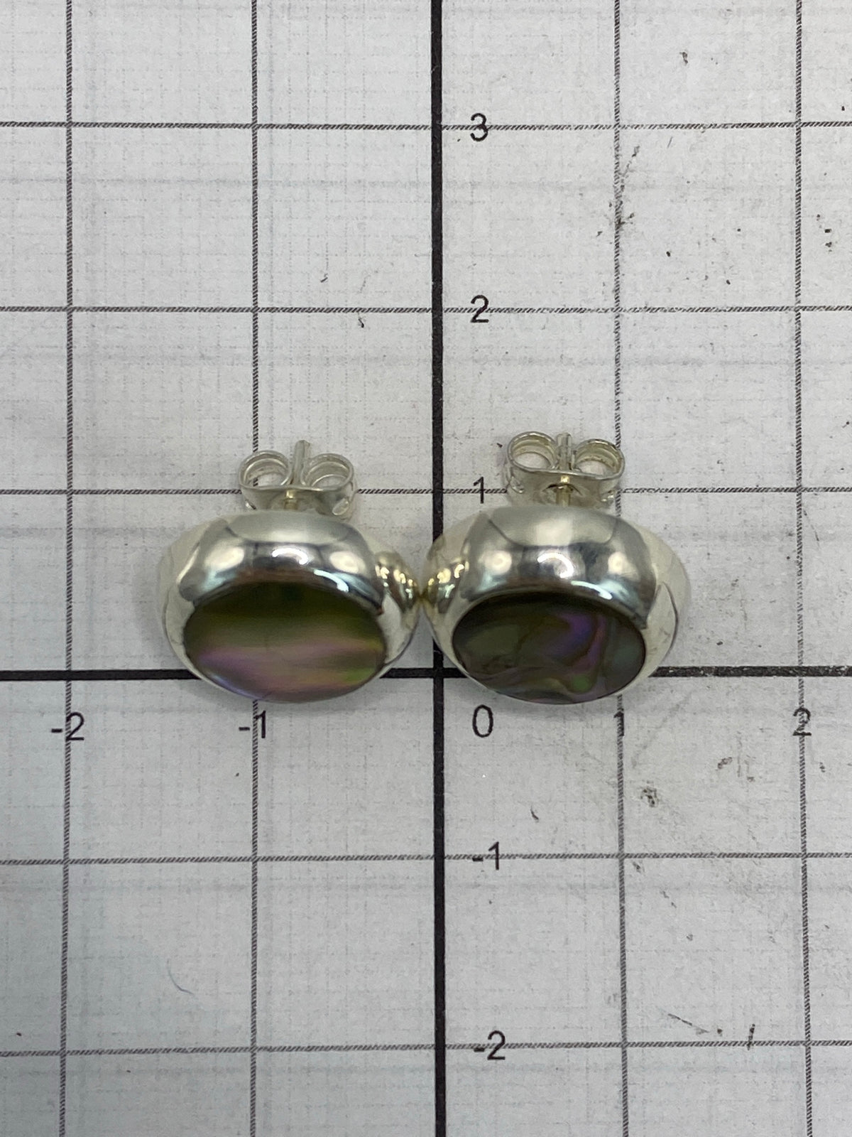 Aretes sobre fondo gris mostrando reflejo de luz en la piedra