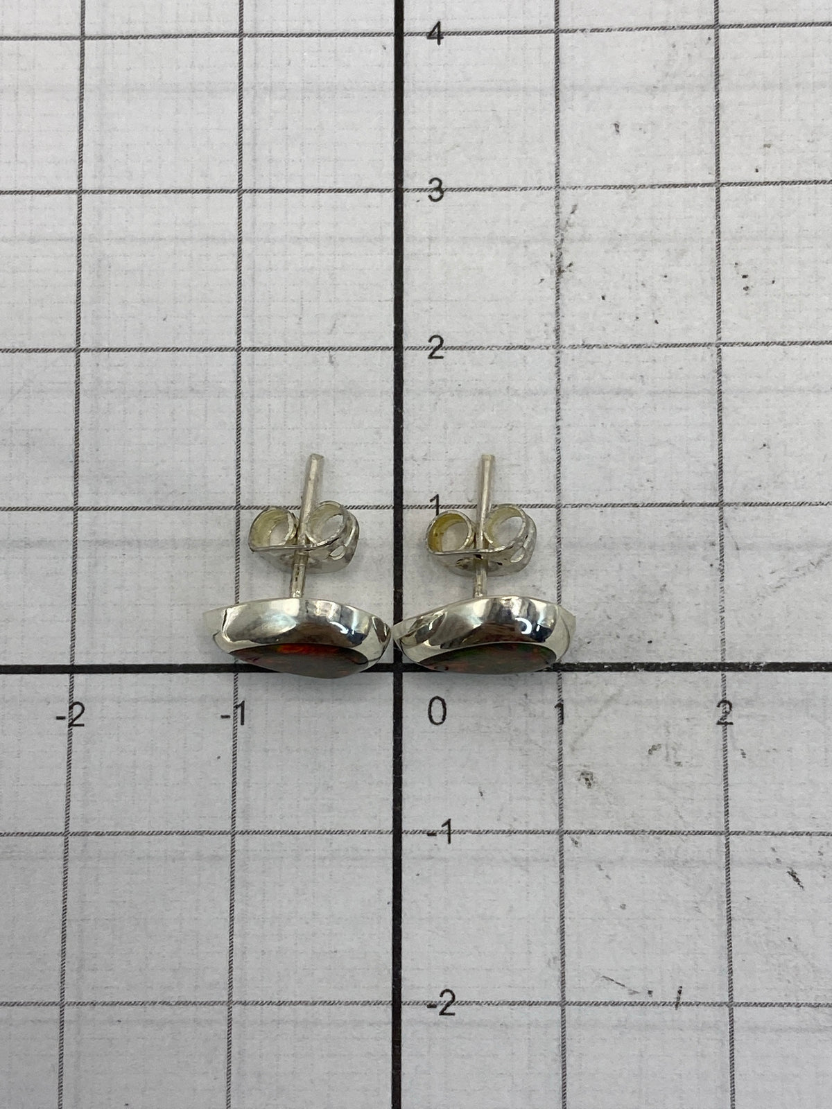 Aretes sobre regla de centímetros y reverso mostrando el Quinto 925
