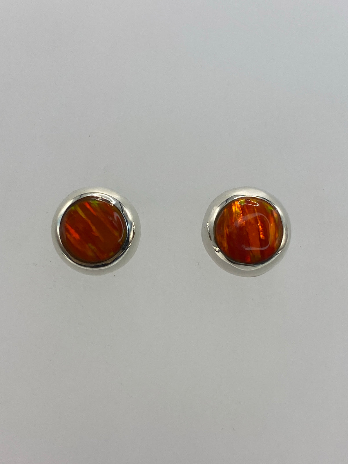 Par de aretes de plata con ópalo de fuego naranja engastado, vista frontal