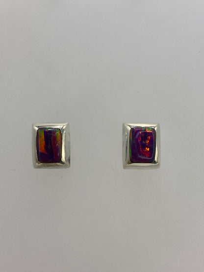 Aretes de plata con ópalo de fuego morado engastados a mano, sobre fondo blanco