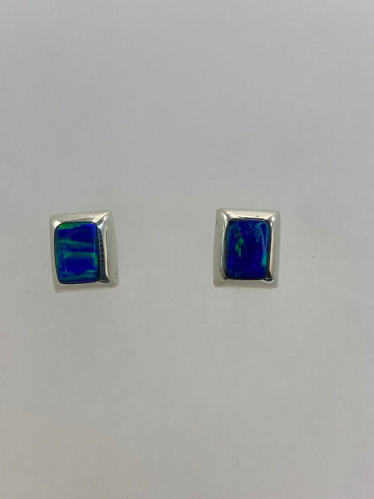 Par de aretes de plata con ópalo de fuego azul cielo engastado, sobre fondo blanco