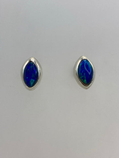 Par de aretes de plata con ópalo de fuego azul sobre fondo blanco