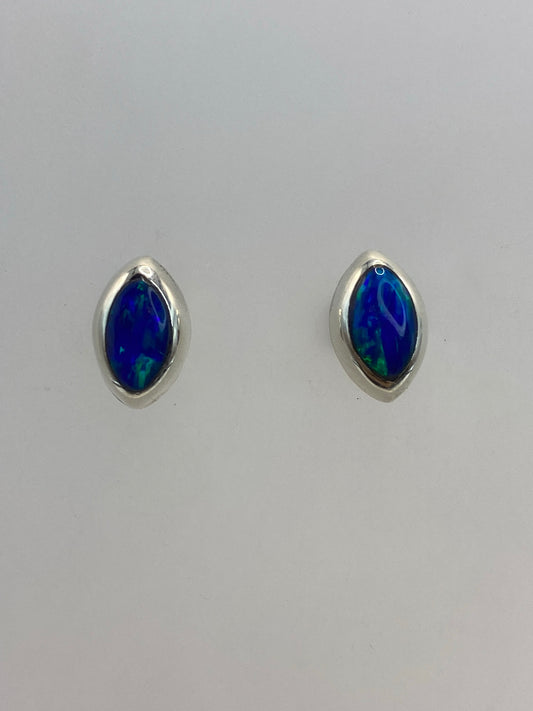 Par de aretes de plata con ópalo de fuego azul sobre fondo blanco