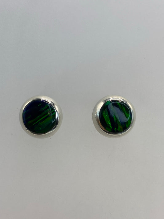 Par de aretes de plata con ópalo de fuego verde, frente a cara blanca