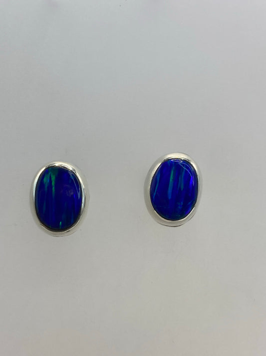 Aretes de plata con ópalo de fuego azul, par completo sobre fondo blanco