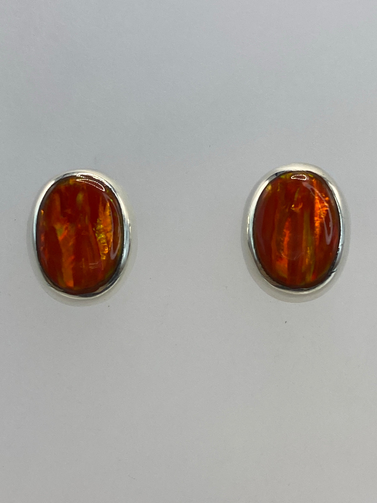Aretes de ópalo de fuego en la oreja, mostrando el color naranja radiante