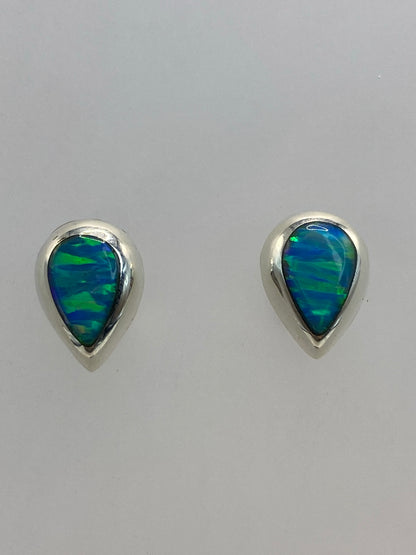 Aretes en par sobre superficie clara, mostrando el brillo azul cielo del ópalo