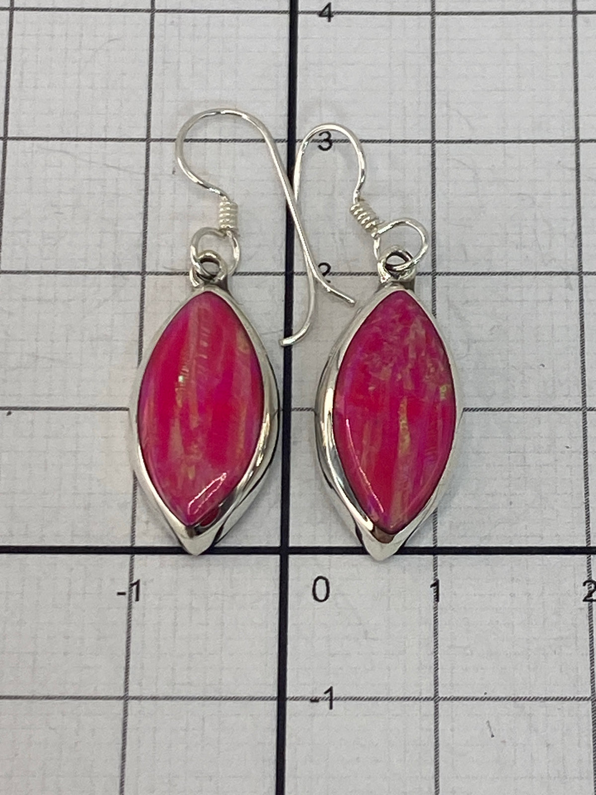 Aretes de ópalo de fuego en la mano, reflejando la luz natural