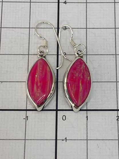 Aretes de ópalo de fuego en la mano, reflejando la luz natural