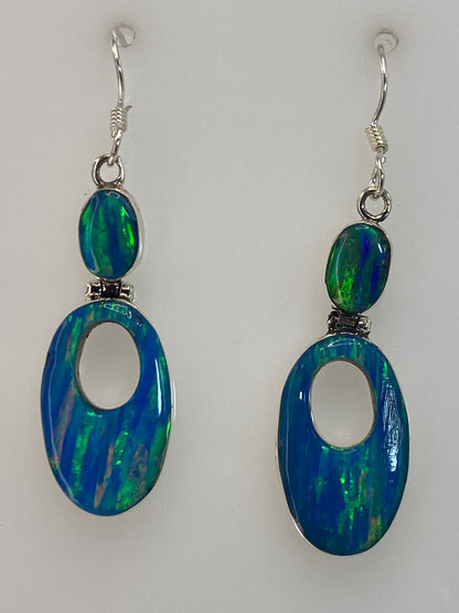 Par de aretes de plata con opalo de fuego azul de 3.8 cm colgando sobre fondo blanco