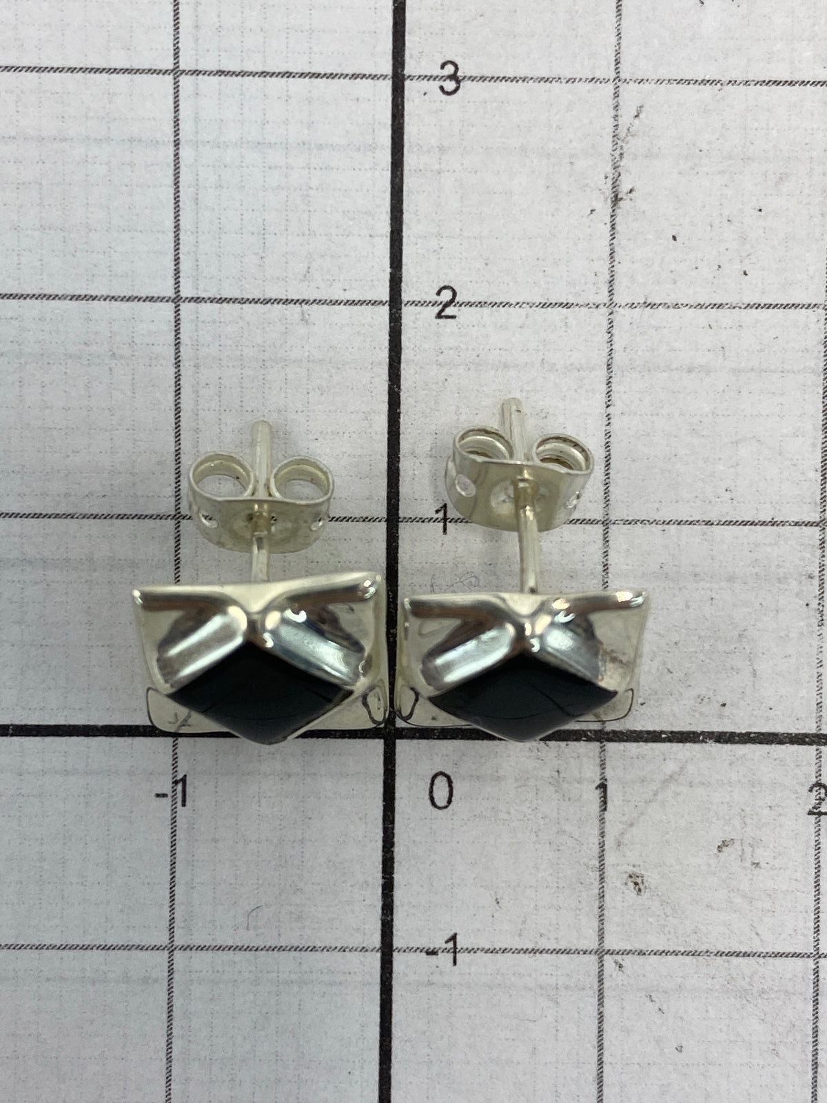 Vista lateral de los aretes destacando el trabajo de plata y la profundidad del diseño