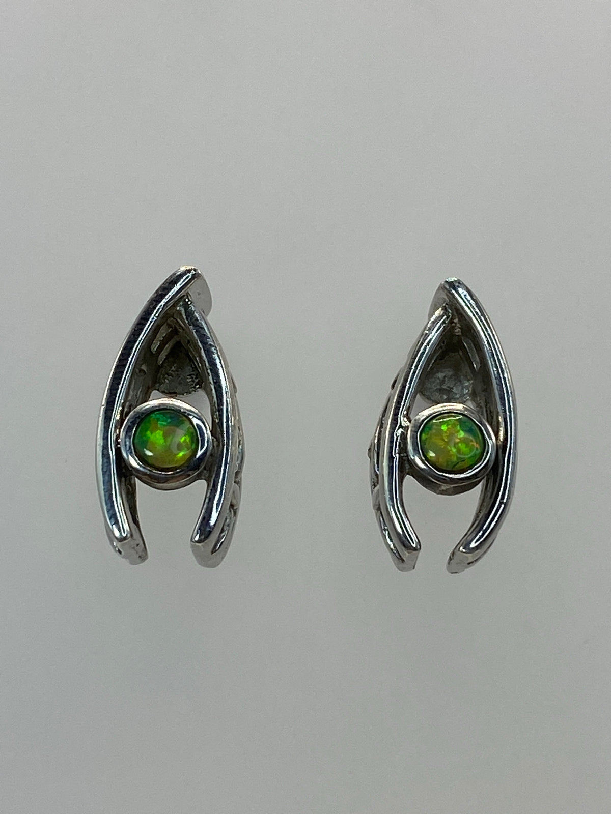 Detalle del ópalo de fuego verde en uno de los aretes, mostrando destellos y tonos cálidos