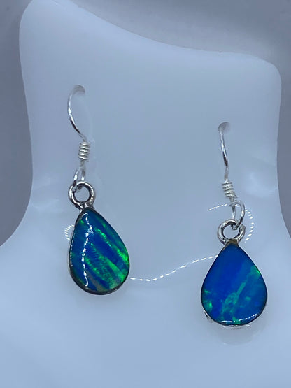 Par de aretes de plata con opalo de fuego azul profundo, colgando de ganchos plateados