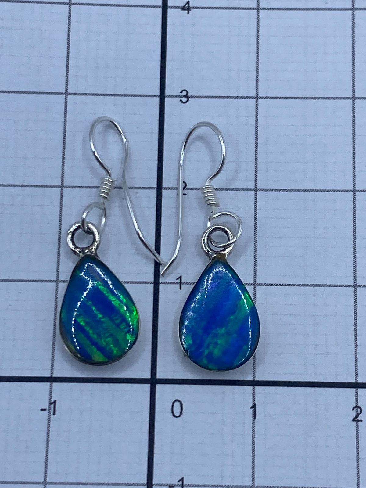 Aretes bajo luz natural mostrando el brillo azul verdoso del opalo de fuego