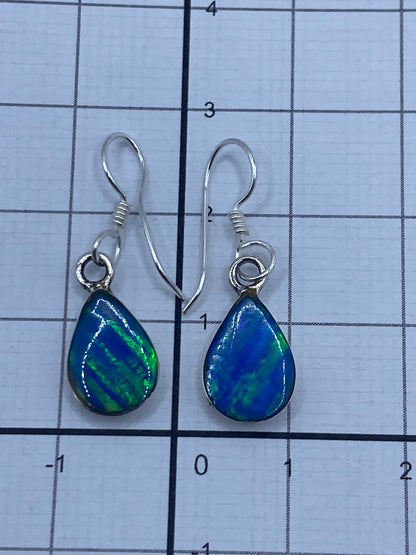 Aretes bajo luz natural mostrando el brillo azul verdoso del opalo de fuego