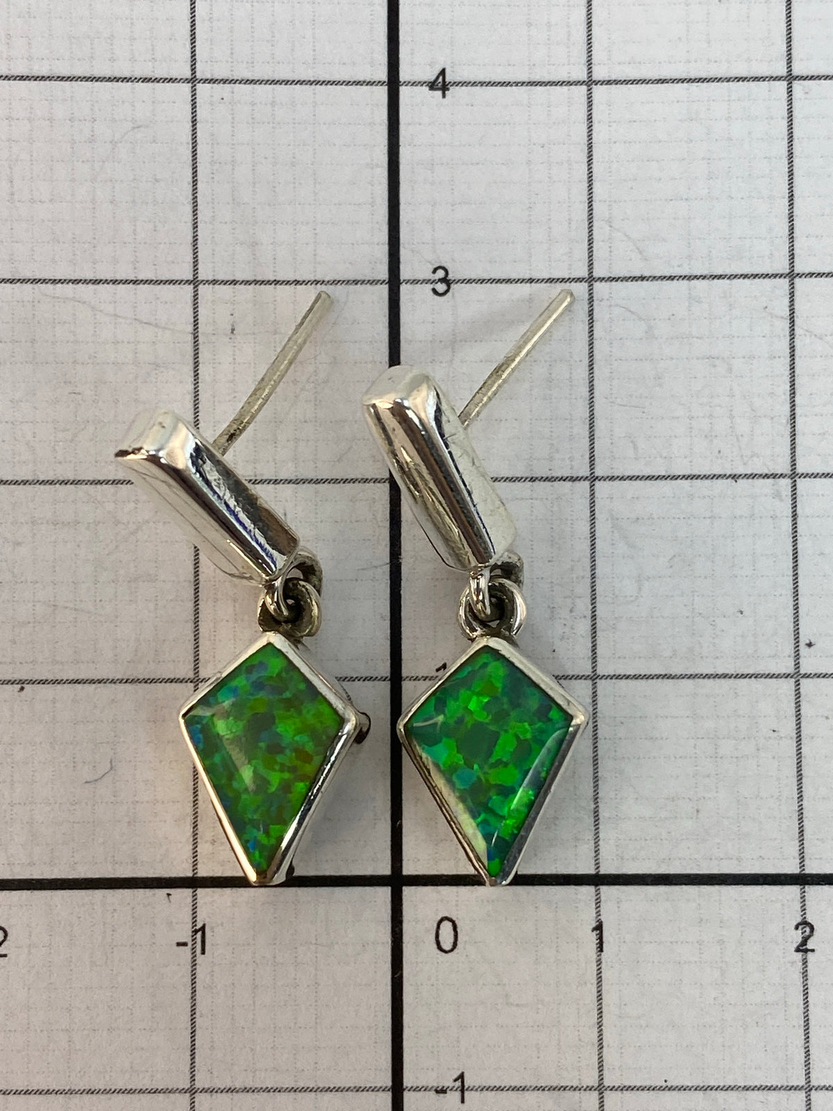 Aretes puestos en oreja, mostrando el largo de 3 cm y el brillo del ópalo