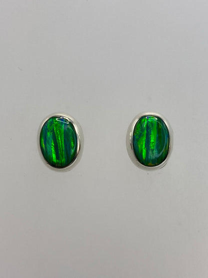 Par de aretes de plata con ópalo de fuego verde en fondo blanco