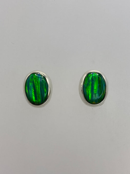 Par de aretes de plata con ópalo de fuego verde en fondo blanco