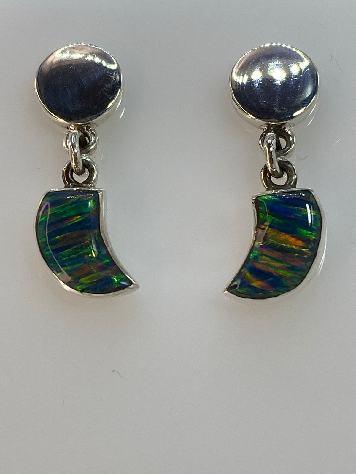 Detalle lateral de los aretes mostrando el Ópalo de Fuego con vetas azul, verde, naranja y dorado