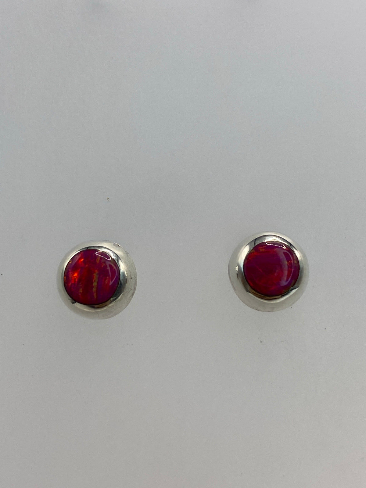 Detalle frontal de los aretes mostrando el brillo rosa del Ópalo de Fuego engastado
