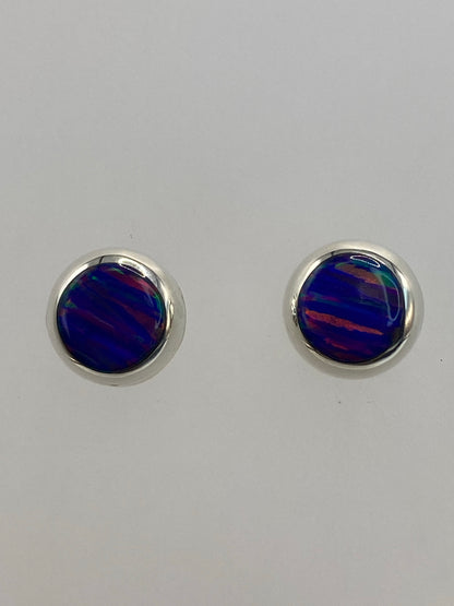 Aretes puestos mostrando el brillo luminoso del ópalo en tonos morada y verde