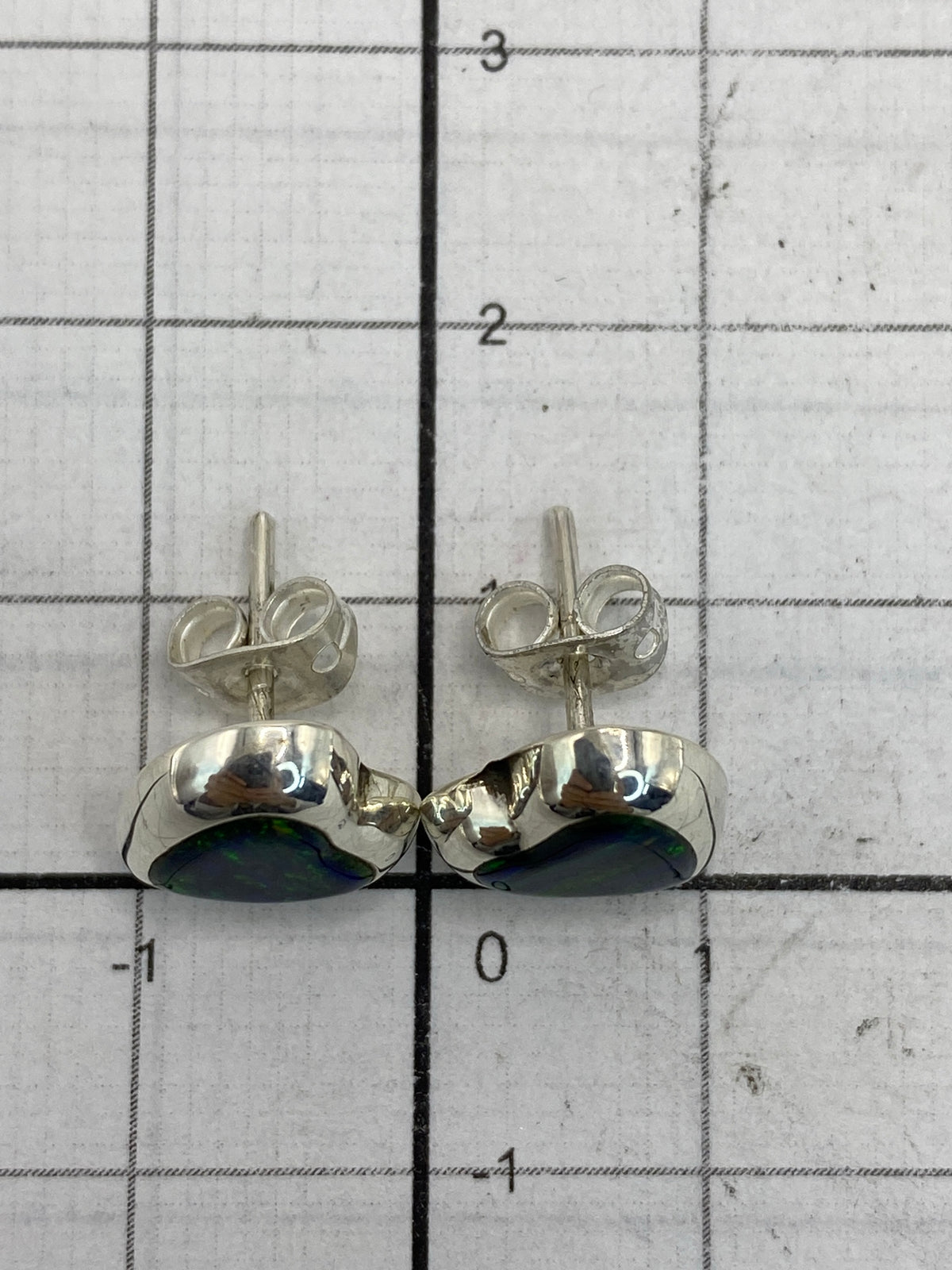 Reverso de los aretes mostrando el Quinto 925 y los broches de presión de plata