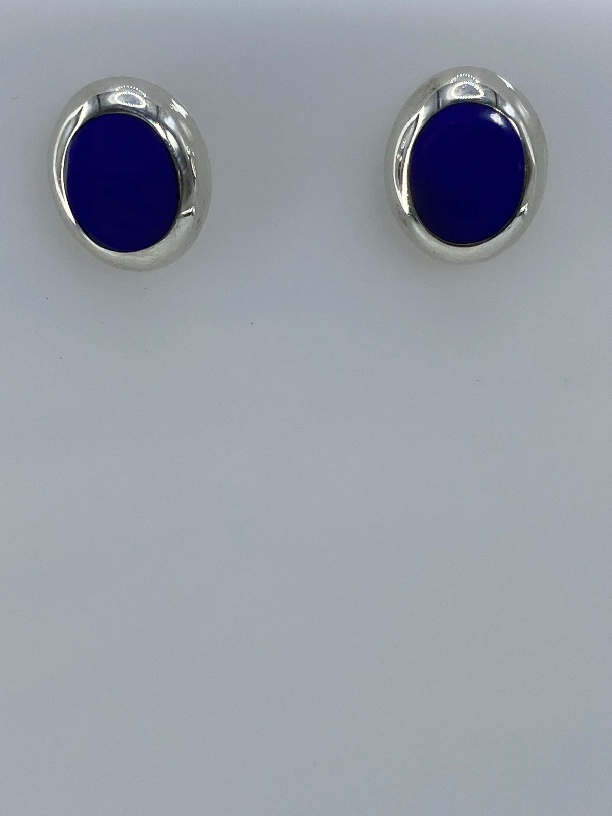 Par de aretes de plata 925 con piedra azul engastada, sobre fondo blanco