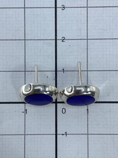 Aretes de plata sobre escala de centímetros mostrando el largo de 1.3 cm