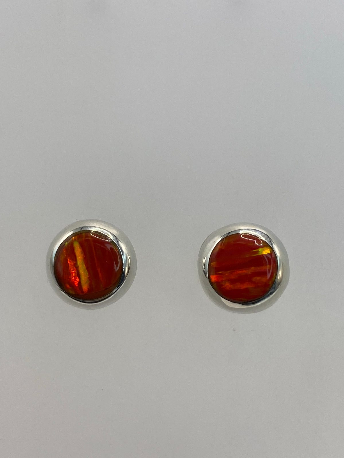 Par de aretes de plata con Ópalo de Fuego naranja, engastados a mano, sobre fondo blanco