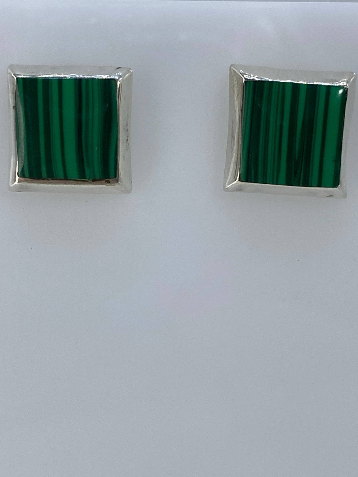 Los dos aretes sobre regla milimétrica mostrando largo de 1.5 cm
