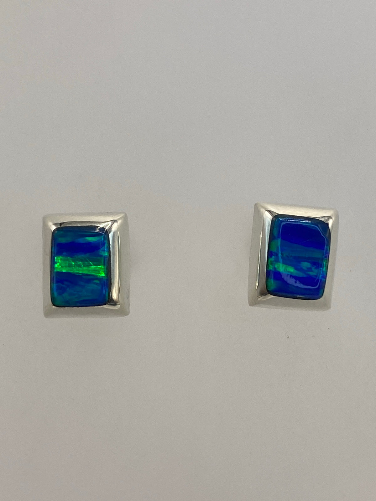 Aretes de plata puestos, luz natural mostrando los destellos azules de la piedra