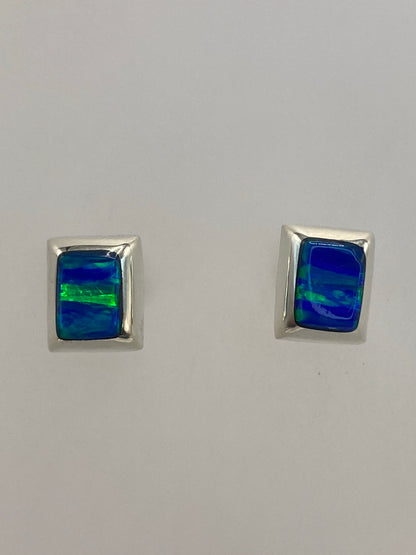 Aretes de plata puestos, luz natural mostrando los destellos azules de la piedra