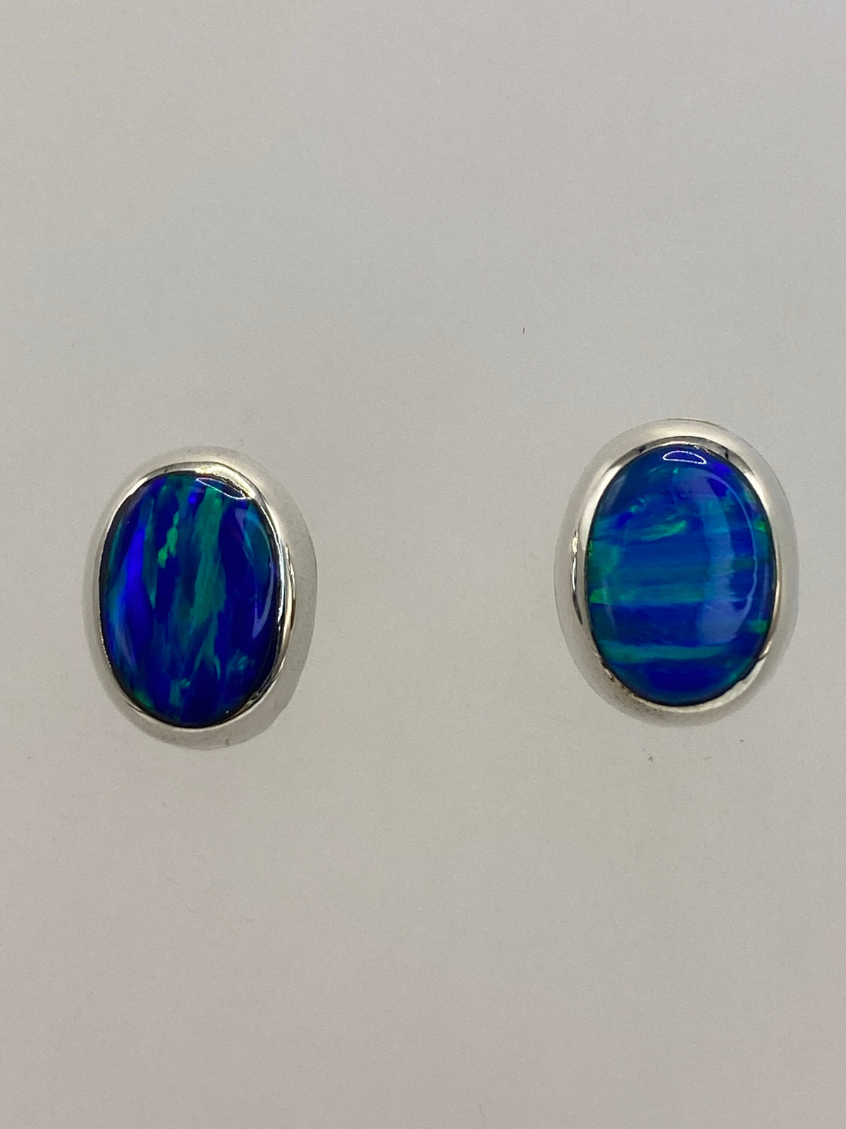 Vista frontal de los dos aretes junto a regla de centímetros, largo 1.4 cm