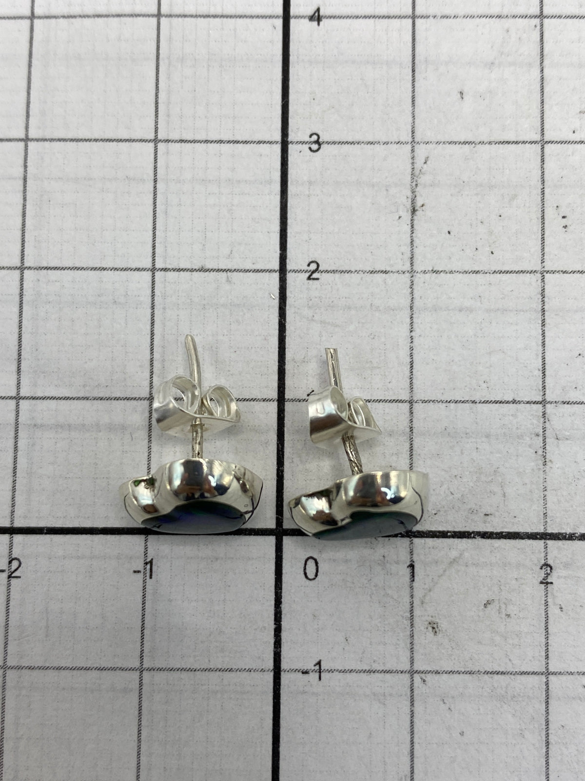 Aretes sobre escala de medidas mostrando su tamaño compacto de 1.4 cm