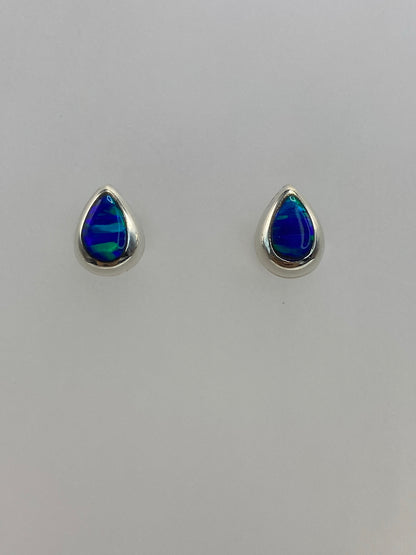 Detalle lateral de aretes de plata con ópalo azul, mostrando el engaste delicado
