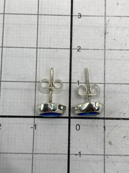 Aretes minimalistas de plata con piedra ópalo azul sobre patrón de medida