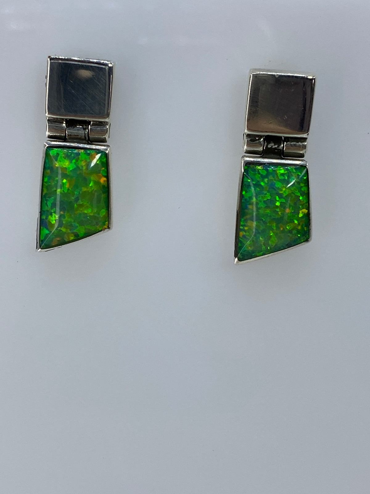 Detalle frontal del ópalo de fuego verde con destellos amarillos y naranjas en cada arete