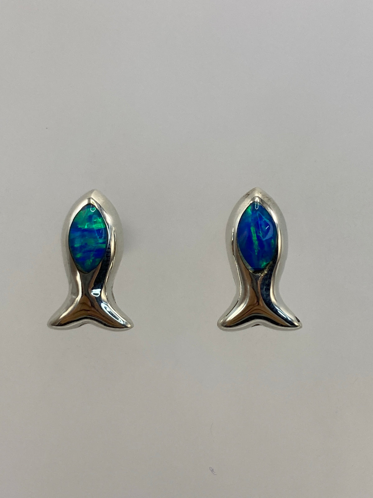 Par de aretes de plata 925 con ópalo de fuego azul engastado a mano sobre fondo blanco