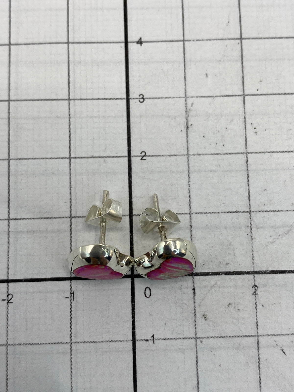 Aretes sobre fondo blanco mostrando el reflejo rosa del Ópalo