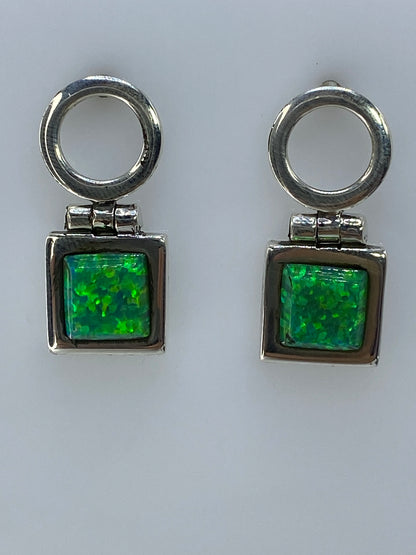 Par de aretes de plata 950 con opalo de fuego verde olivo, colgando sobre fondo blanco