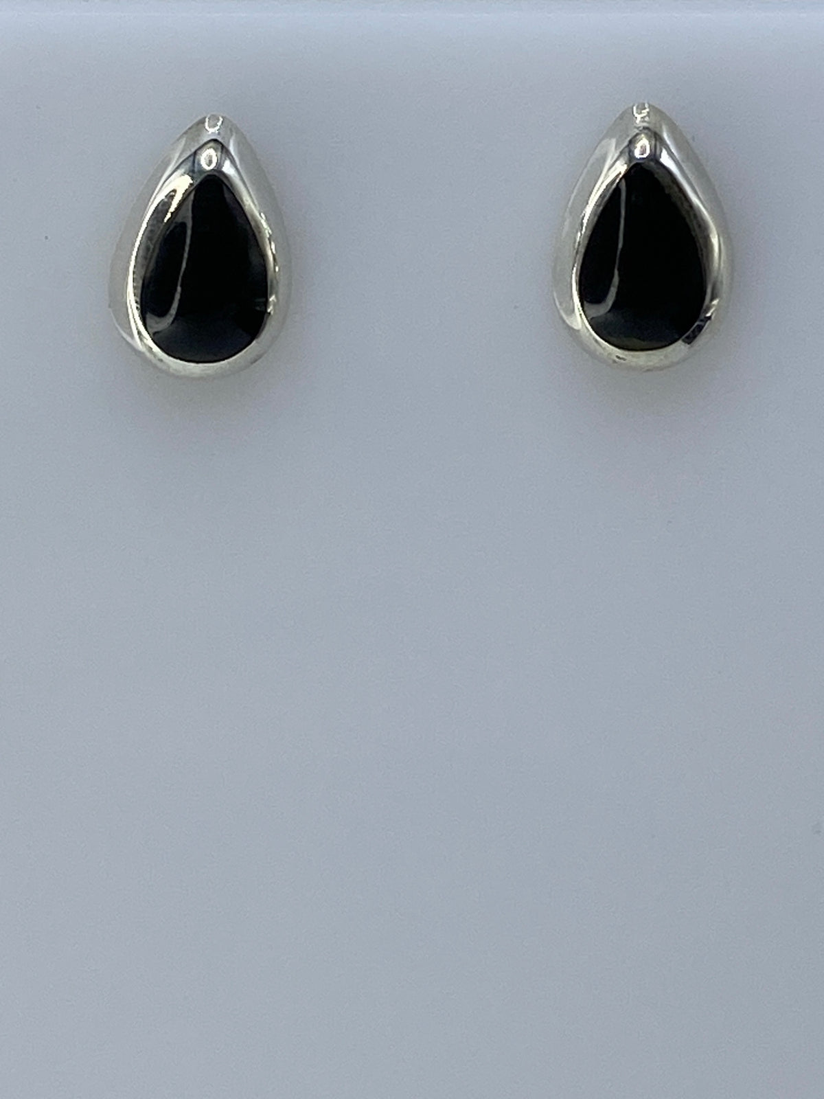 Par de aretes de plata con piedra negra engastada, vista frontal sobre fondo blanco