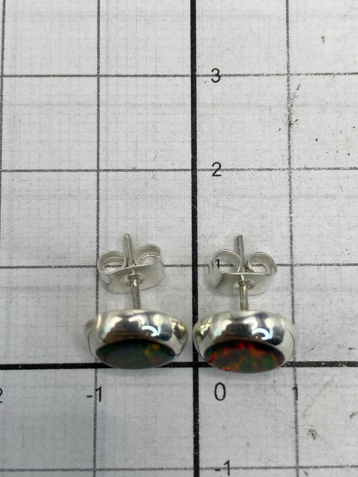 Aretes sobre superficie blanca con escala de medida, mostrando el largo de 1.3 cm