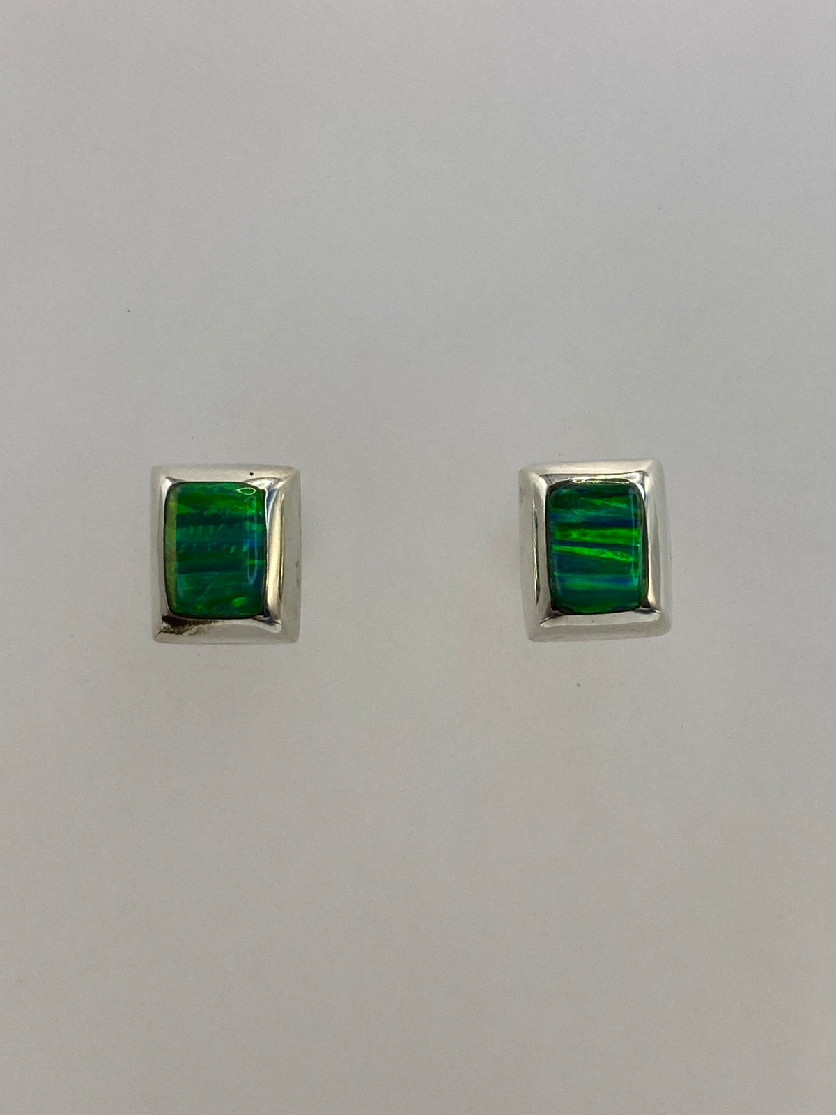Par de aretes de plata 950 con opalo de fuego verde en fondo blanco