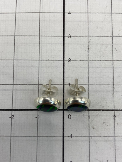Los aretes al lado de una moneda para escala de tamaño real