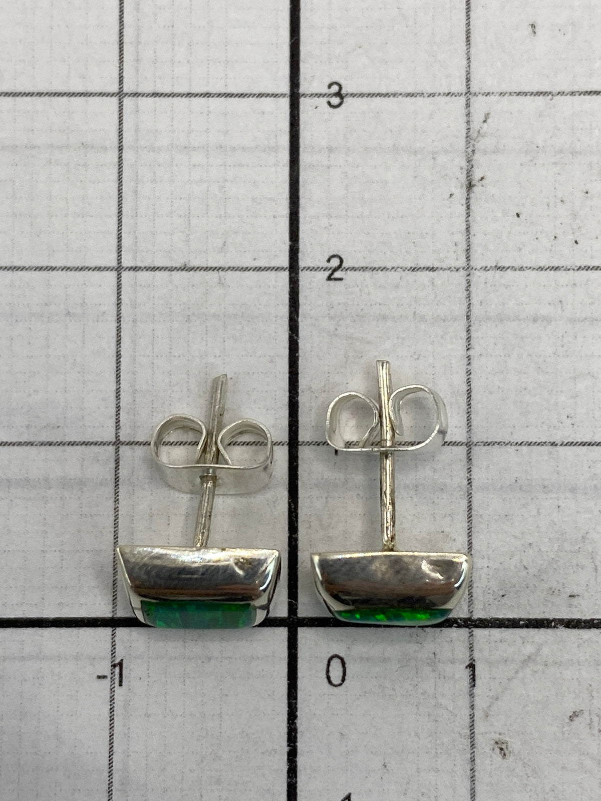 Los aretes colocados sobre fondo claro para mostrar tamaño y color del ópal