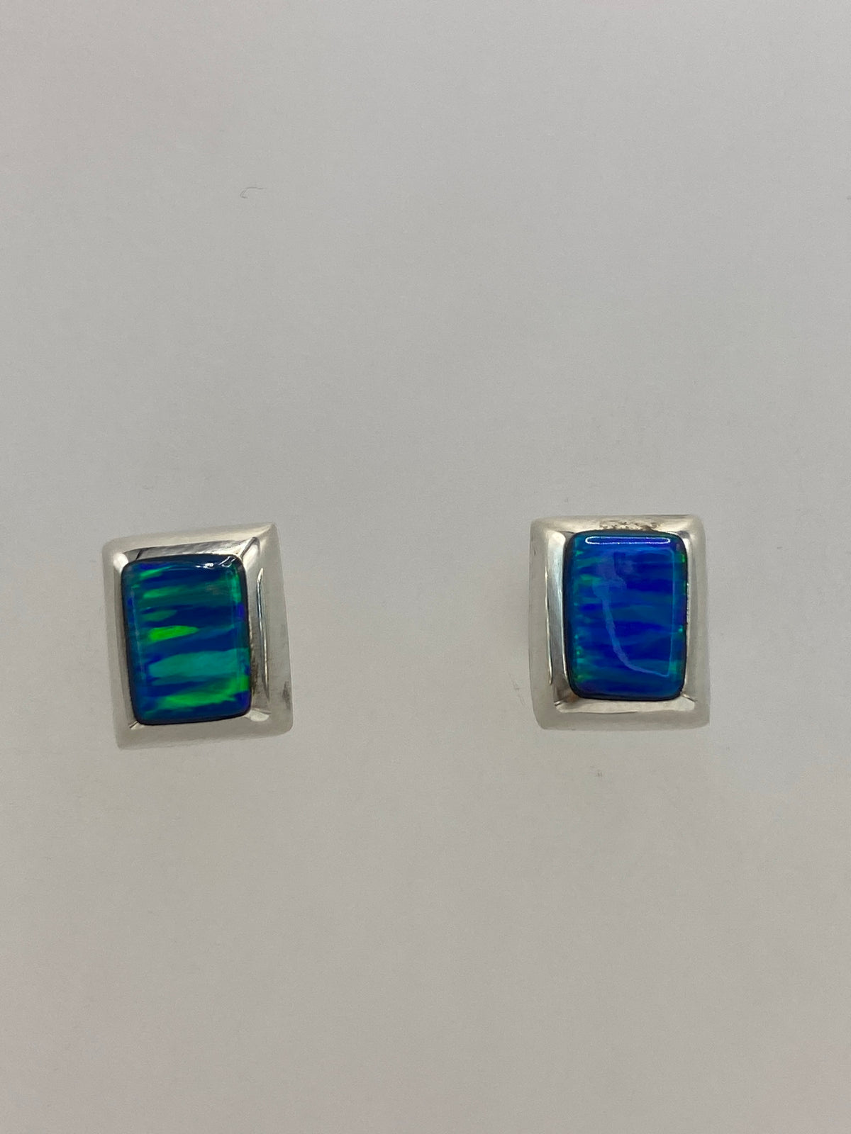 Vista frontal del par de aretes delicados con piedra azul engastada
