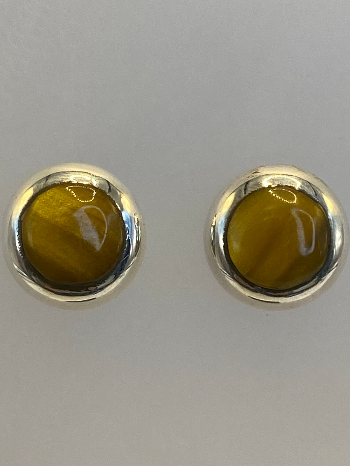 Aretes sobre medidor de escala mostrando su tamaño minimalista de 1.4 cm