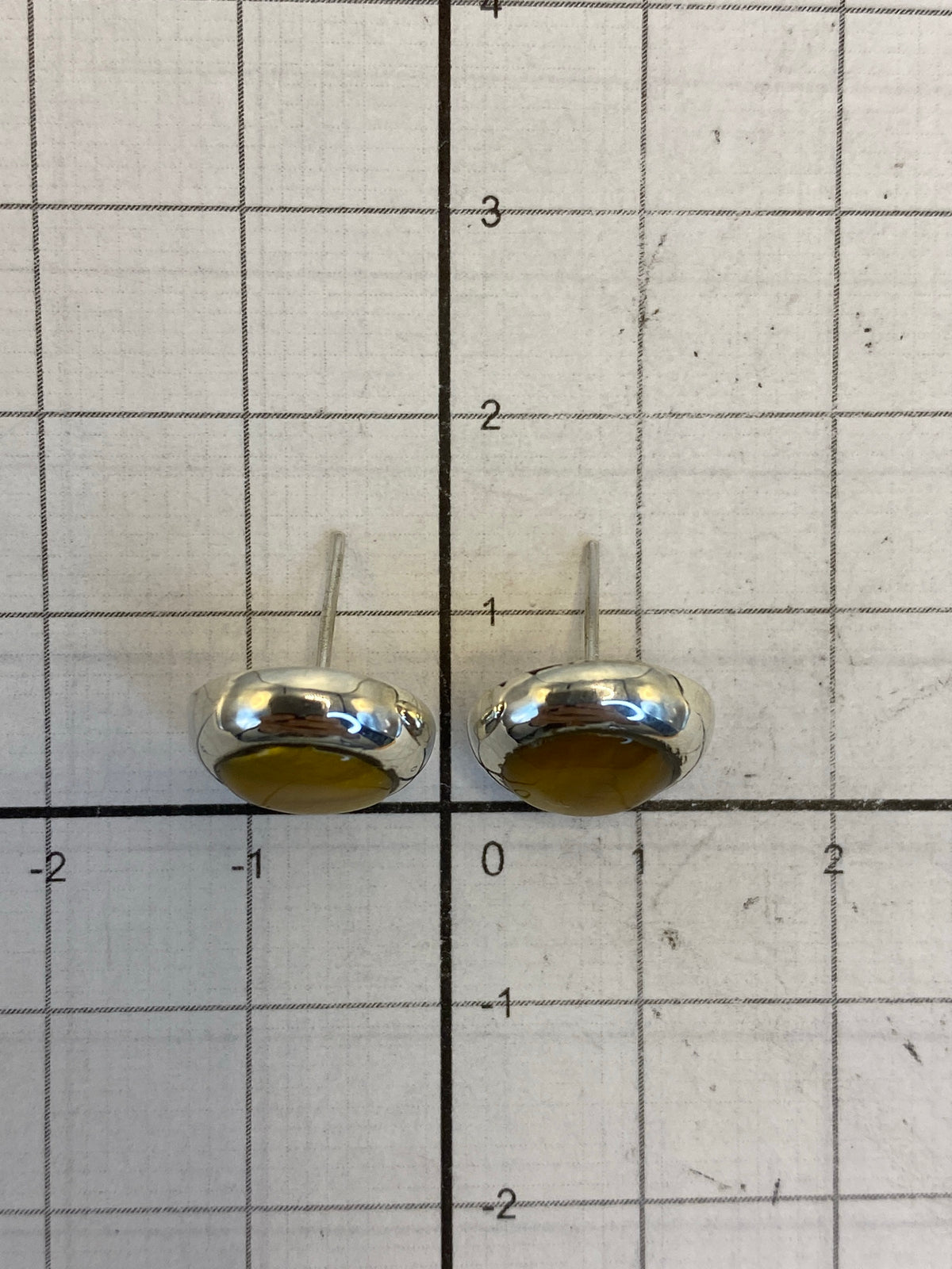 Reverso de los aretes mostrando el Quinto 925 y el cierre de poste de plata